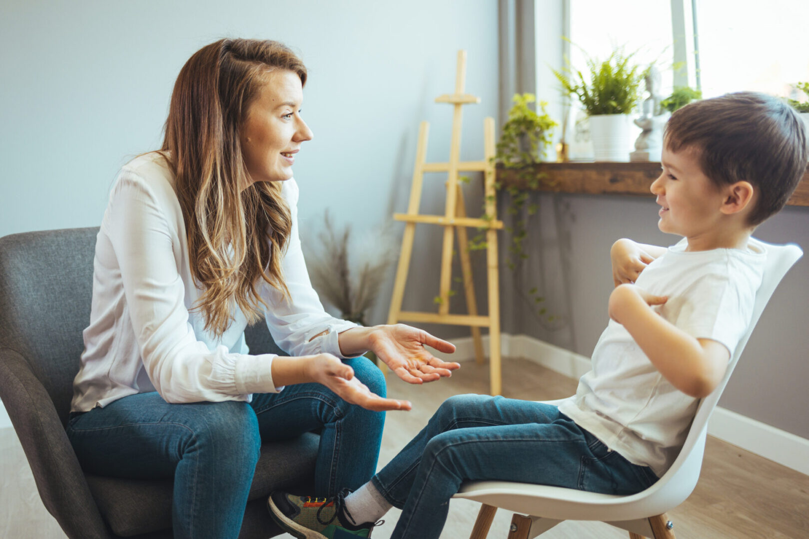 Woman talking to a young boy indoors.