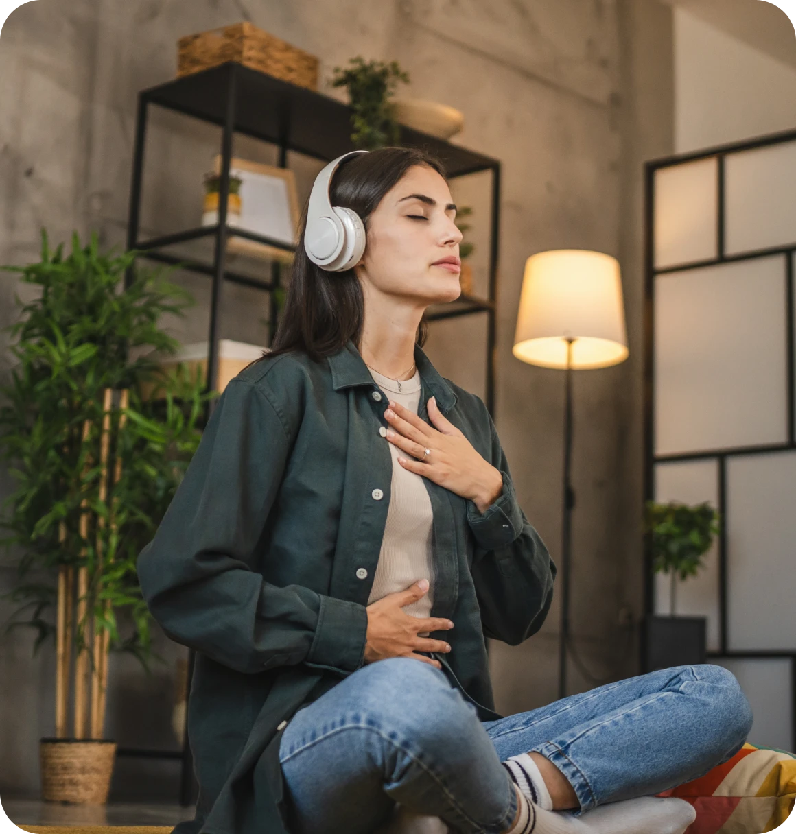 Woman meditating with headphones in cozy room.